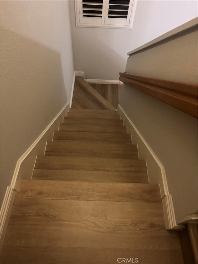 staircase with visible vents, baseboards, and wood finished floors