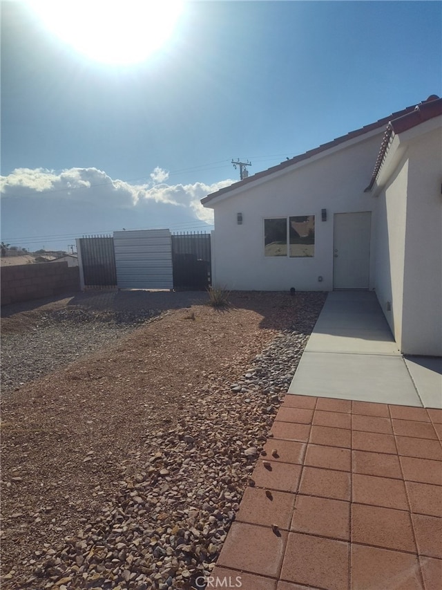 exterior space featuring a gate, fence, and stucco siding