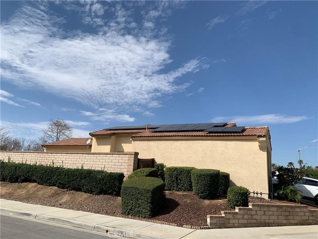 1561 Palma Bonita, Perris, CA 92571 - view of home's exterior featuring stucco siding, fence, solar panels, and a tiled roof