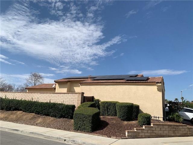 1561 Palma Bonita, Perris, CA 92571 - view of home's exterior featuring stucco siding, fence, solar panels, and a tiled roof