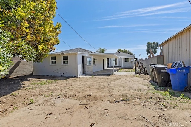 back of property featuring stucco siding and fence
