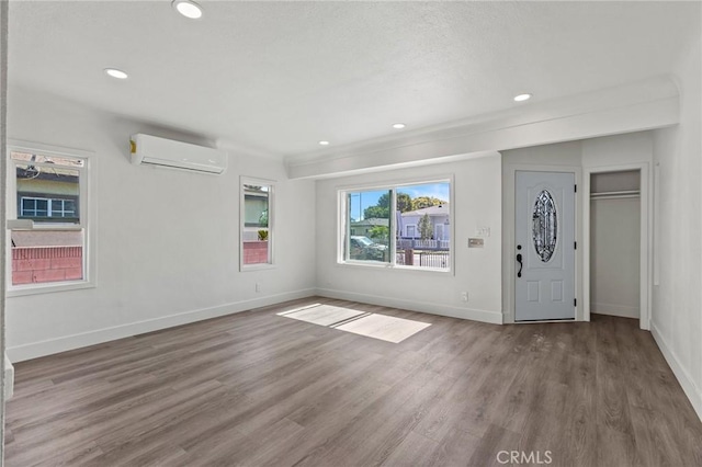 entrance foyer featuring recessed lighting, wood finished floors, an AC wall unit, and baseboards