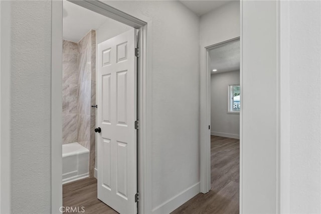 hallway featuring baseboards and wood finished floors