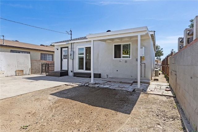 back of house featuring a fenced backyard, a patio, and stucco siding