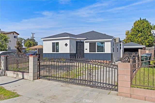 view of front of home with stucco siding, a shingled roof, a gate, and a fenced front yard