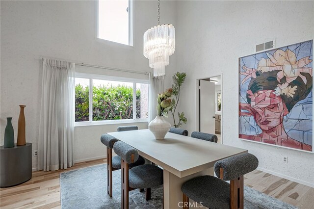 27072 Esward Dr, Calabasas, CA 91301 - dining space featuring a towering ceiling, light wood-style floors, a chandelier, and baseboards
