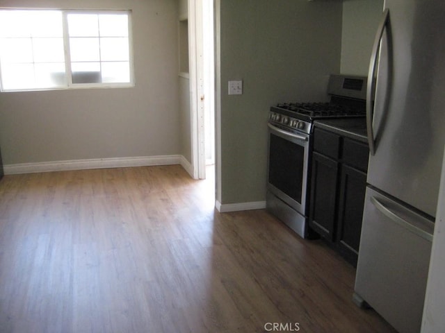kitchen featuring baseboards, appliances with stainless steel finishes, and wood finished floors