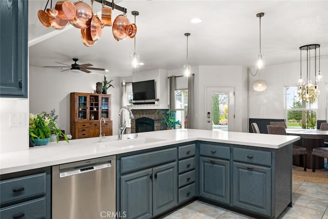 kitchen with light countertops, a sink, a fireplace, stainless steel dishwasher, and open floor plan