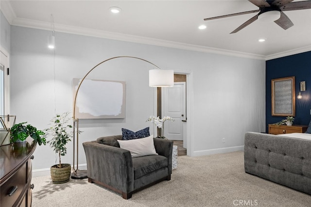 living area with baseboards, ornamental molding, ceiling fan, and carpet flooring