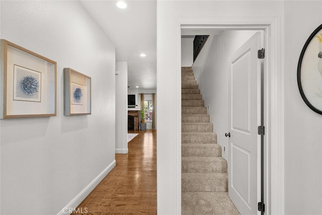staircase with baseboards, a fireplace, wood finished floors, and recessed lighting