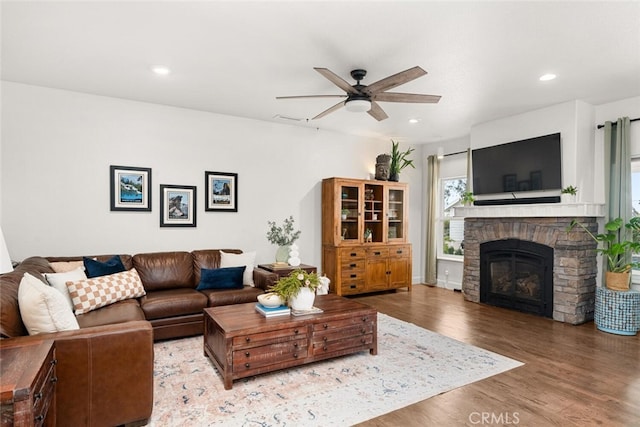 living room featuring a stone fireplace, wood finished floors, ceiling fan, and recessed lighting