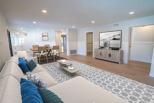 living area featuring wood finished floors, visible vents, and a wainscoted wall