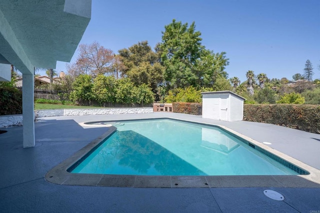 view of pool featuring a storage unit, a fenced in pool, an outbuilding, a fenced backyard, and a patio area