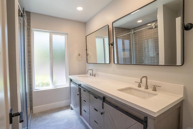 full bath with baseboards, a sink, double vanity, and a stall shower