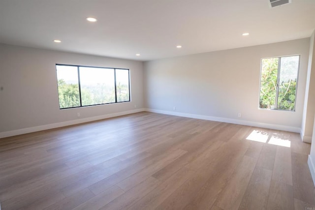 spare room with light wood-type flooring, plenty of natural light, and recessed lighting