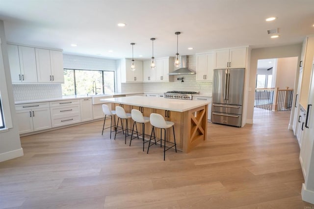 kitchen with stainless steel fridge, tasteful backsplash, wall chimney range hood, and a wealth of natural light
