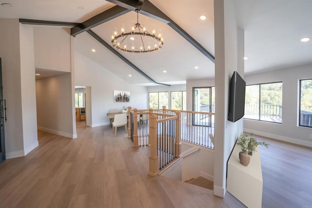 interior space with baseboards, an inviting chandelier, beam ceiling, and light wood-style flooring