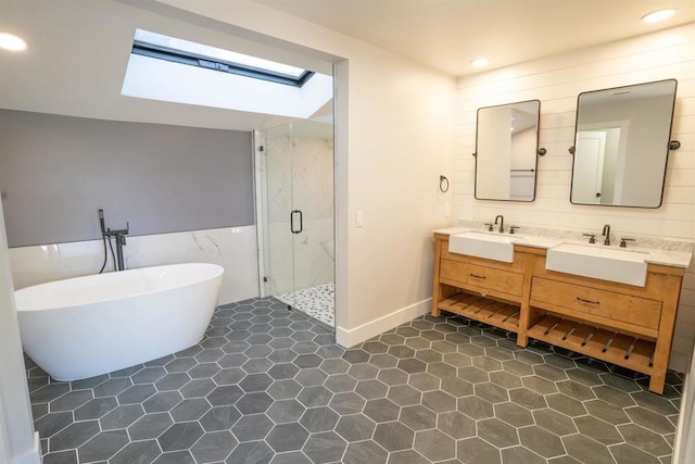full bath with tile walls, a sink, a marble finish shower, and a skylight