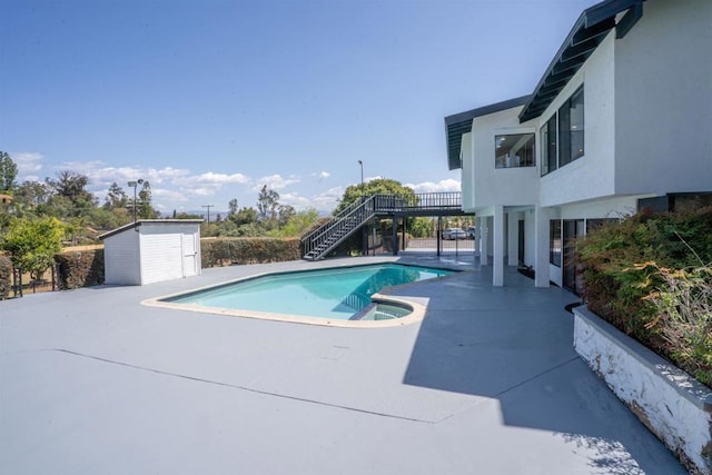 pool featuring stairway, a shed, an outbuilding, an in ground hot tub, and a patio