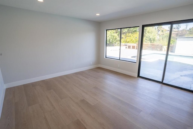 unfurnished room with recessed lighting, wood finished floors, and baseboards