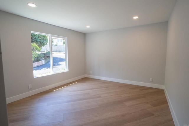unfurnished room with light wood finished floors, baseboards, and recessed lighting