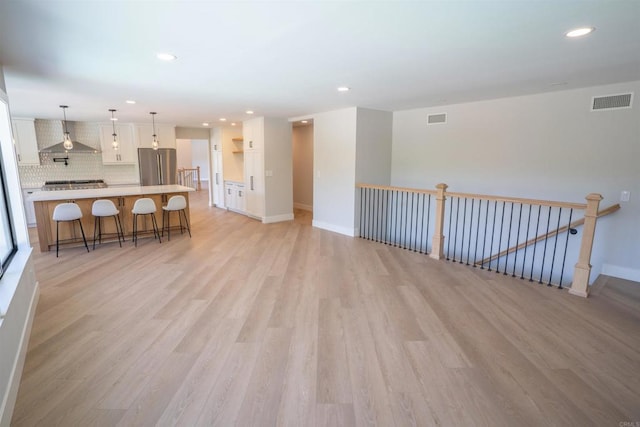 living room featuring light wood-style flooring, visible vents, and baseboards