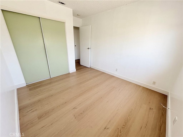 18131 Camino Bello Unit 4, Rowland Heights, CA 91748 - unfurnished bedroom featuring light wood-style flooring, a closet, and a textured ceiling