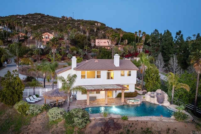 15881 Broad Oaks Rd, El Cajon, CA 92021 - back of house with an in-ground hot tub, a chimney, stucco siding, fence, and a standing seam roof
