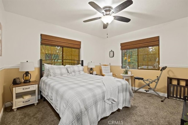 bedroom featuring dark carpet, a ceiling fan, baseboards, and multiple windows