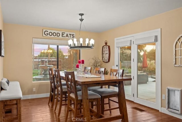 dining space with hardwood / wood-style floors, visible vents, baseboards, and a chandelier