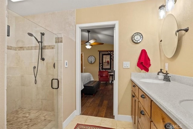 ensuite bathroom featuring ceiling fan, a stall shower, ensuite bathroom, tile patterned floors, and a sink