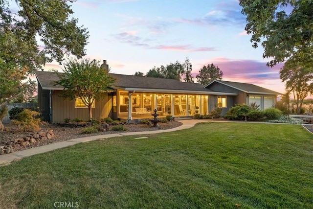 back of house with an attached garage and a lawn