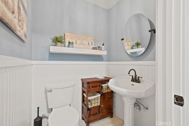 bathroom featuring wainscoting, toilet, and a sink