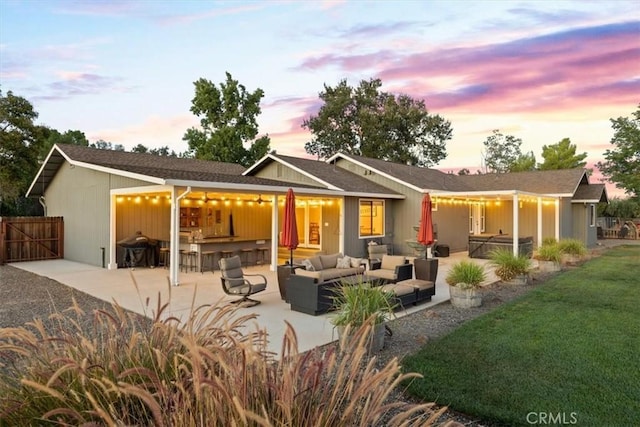 back of house at dusk featuring a patio area, an outdoor hangout area, outdoor dry bar, and fence