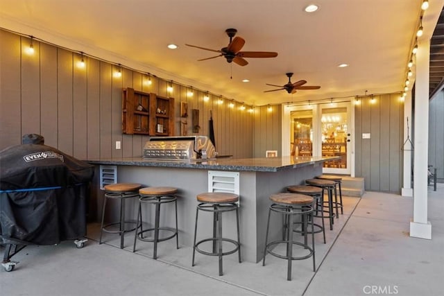 exterior space featuring concrete floors, a kitchen bar, recessed lighting, a peninsula, and a ceiling fan
