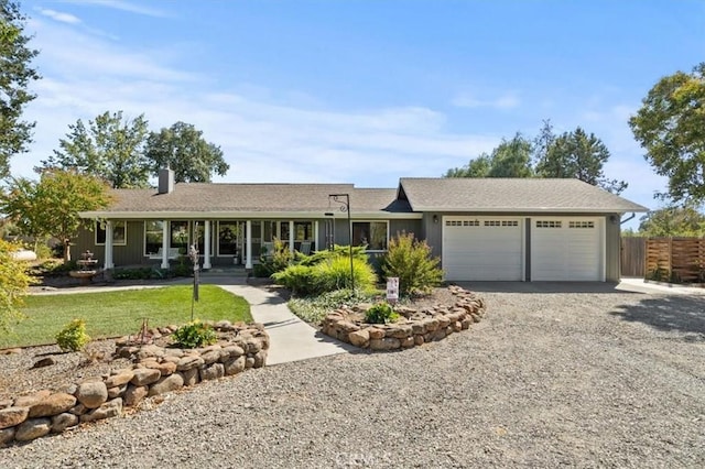 ranch-style house featuring driveway, a chimney, an attached garage, and fence