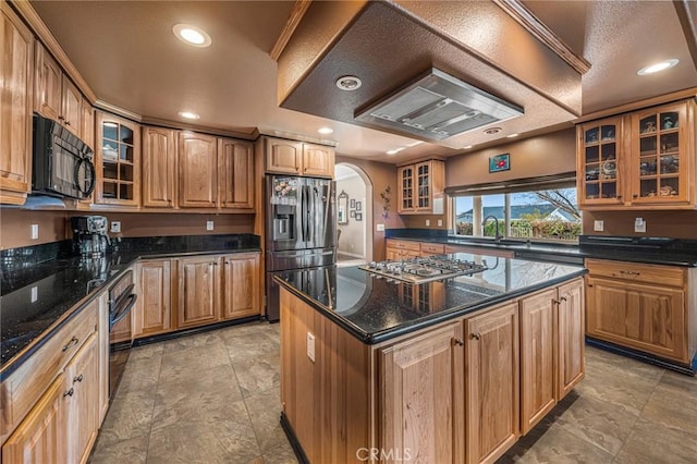 kitchen with a sink, glass insert cabinets, a center island, arched walkways, and black appliances
