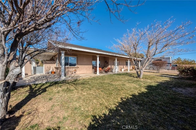 rear view of house featuring a lawn, fence, a patio, and stucco siding