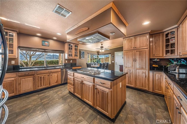 kitchen with visible vents, a center island, a sink, glass insert cabinets, and stainless steel appliances
