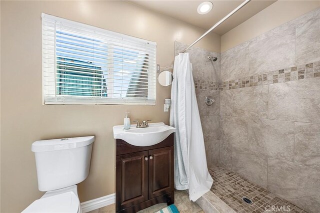 full bathroom featuring toilet, tiled shower, and vanity