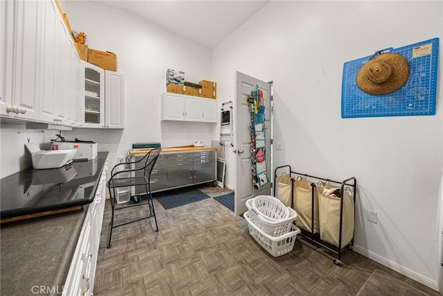 interior space featuring baseboards, lofted ceiling, white cabinets, and glass insert cabinets