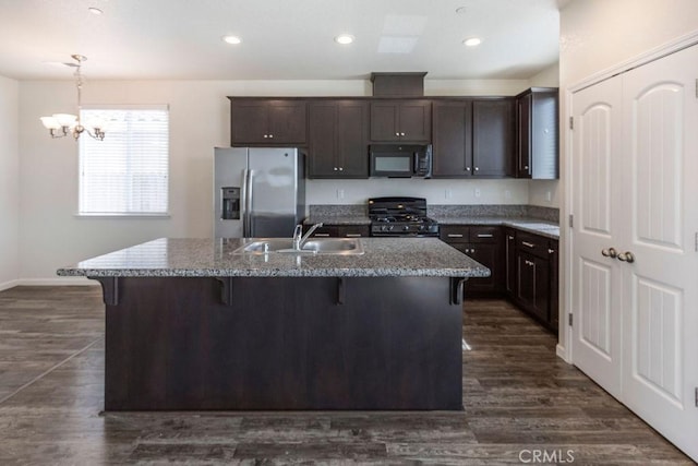 kitchen featuring a sink, a kitchen breakfast bar, range with gas cooktop, stainless steel fridge, and black microwave