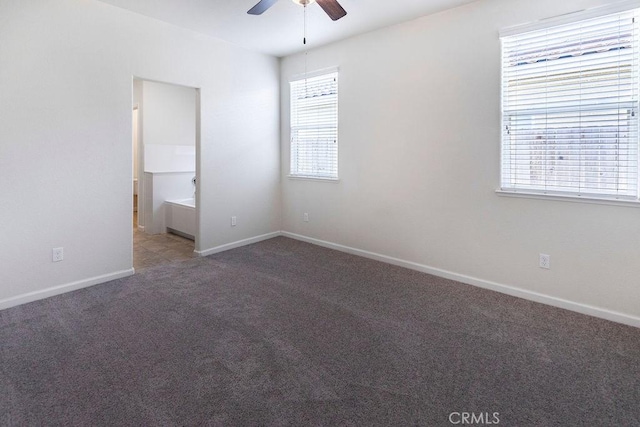 carpeted spare room with a ceiling fan and baseboards