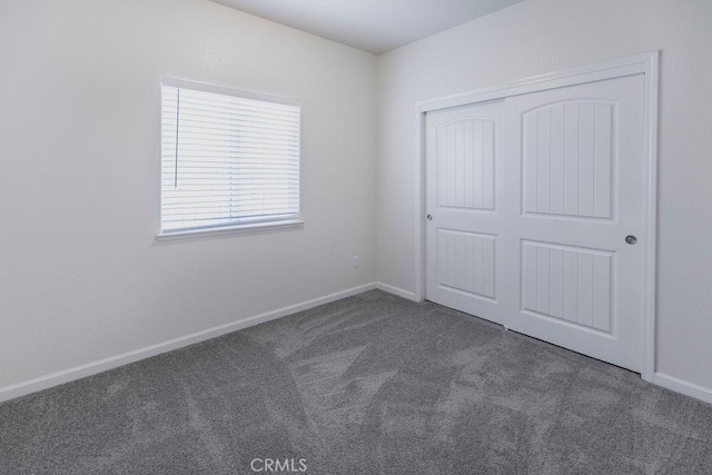 unfurnished bedroom with a closet, carpet flooring, and baseboards