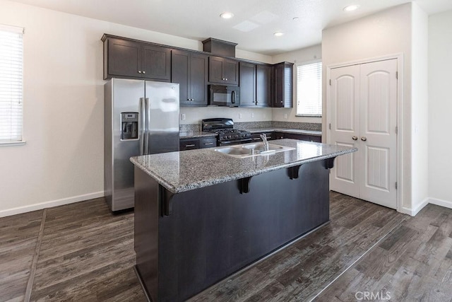 kitchen with a breakfast bar, stainless steel refrigerator with ice dispenser, a sink, black microwave, and gas range