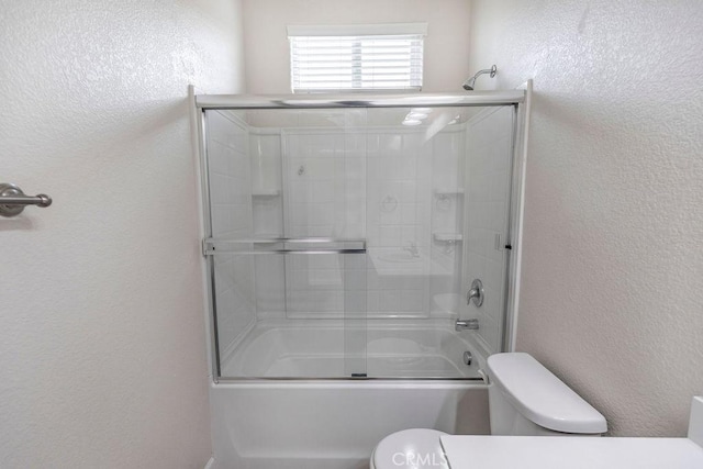 full bath featuring toilet, bath / shower combo with glass door, and a textured wall