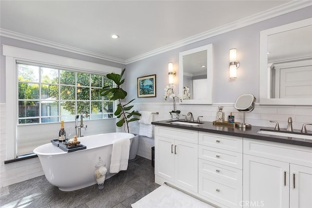 full bathroom featuring a sink, tile walls, double vanity, and a freestanding bath