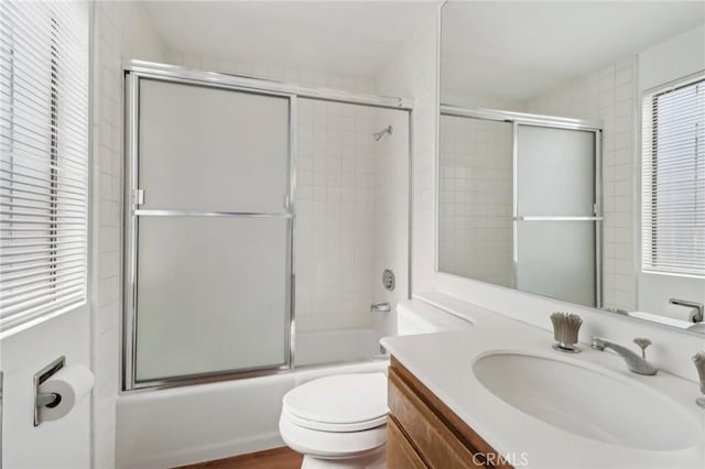 bathroom featuring vanity, toilet, and bath / shower combo with glass door