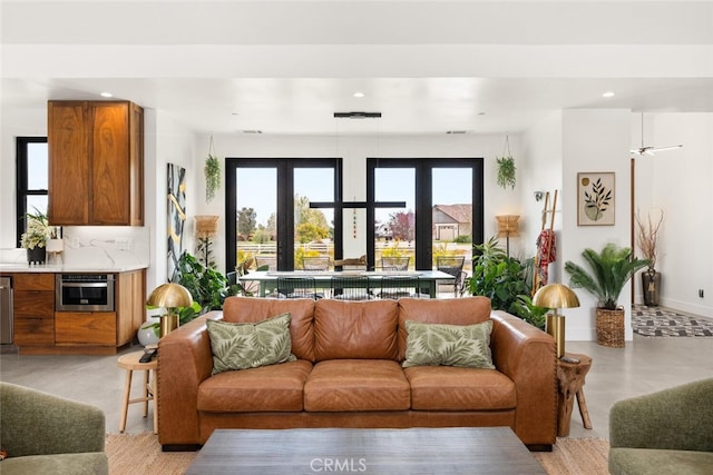 living room with baseboards, recessed lighting, french doors, and concrete flooring