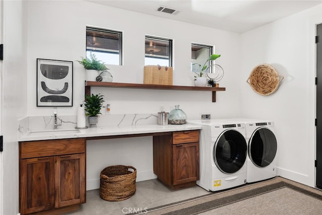 washroom with visible vents, washing machine and dryer, cabinet space, and a sink